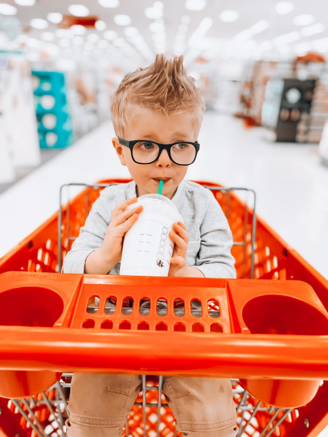 Boy in shopping cart with glasses enjoying the ride