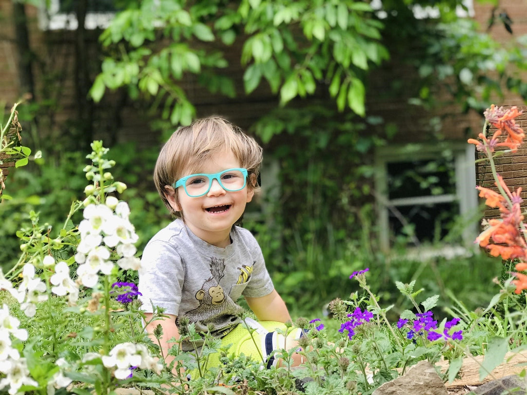 Child with glasses laughing in garden