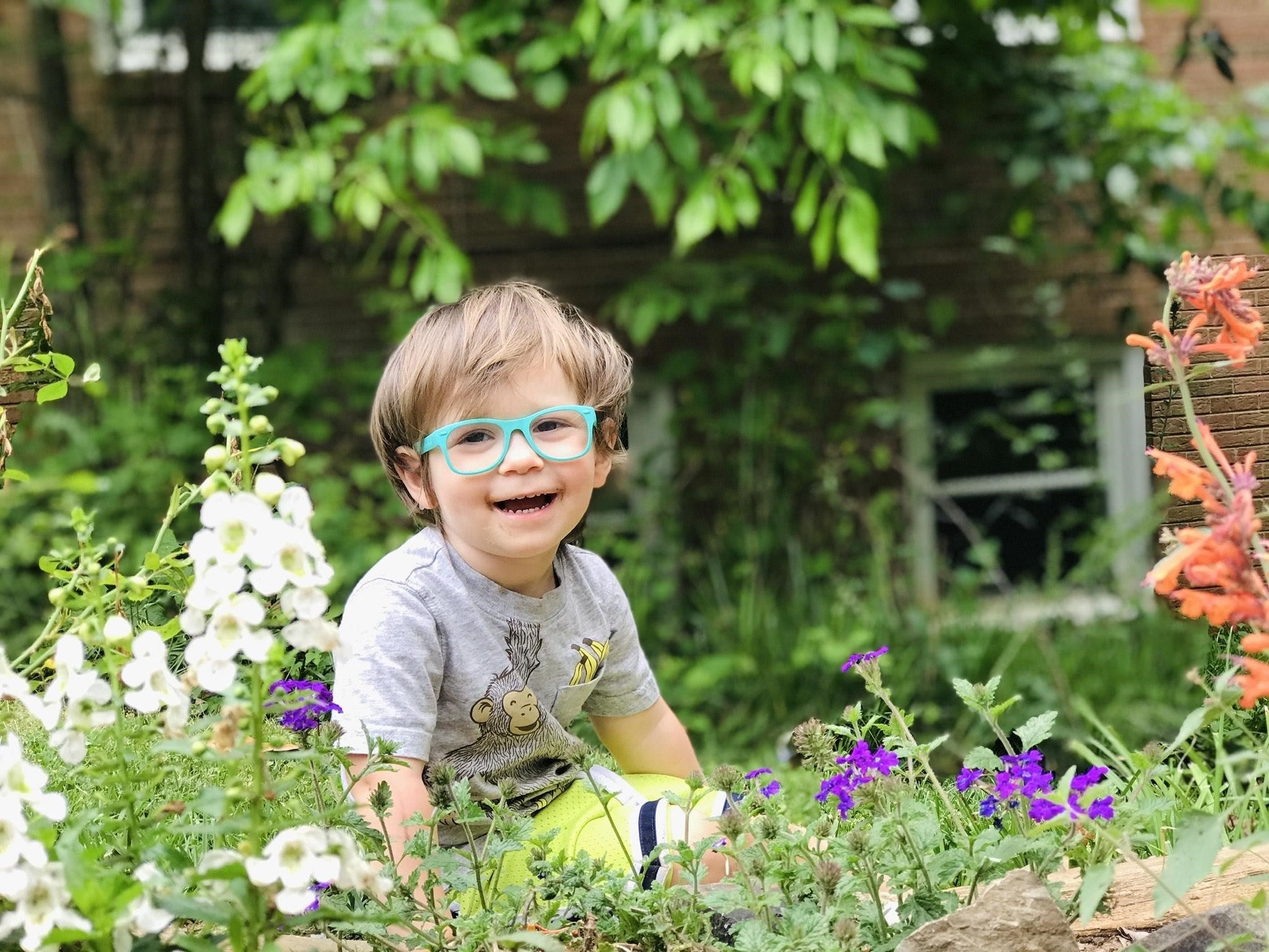 Child with glasses laughing in garden