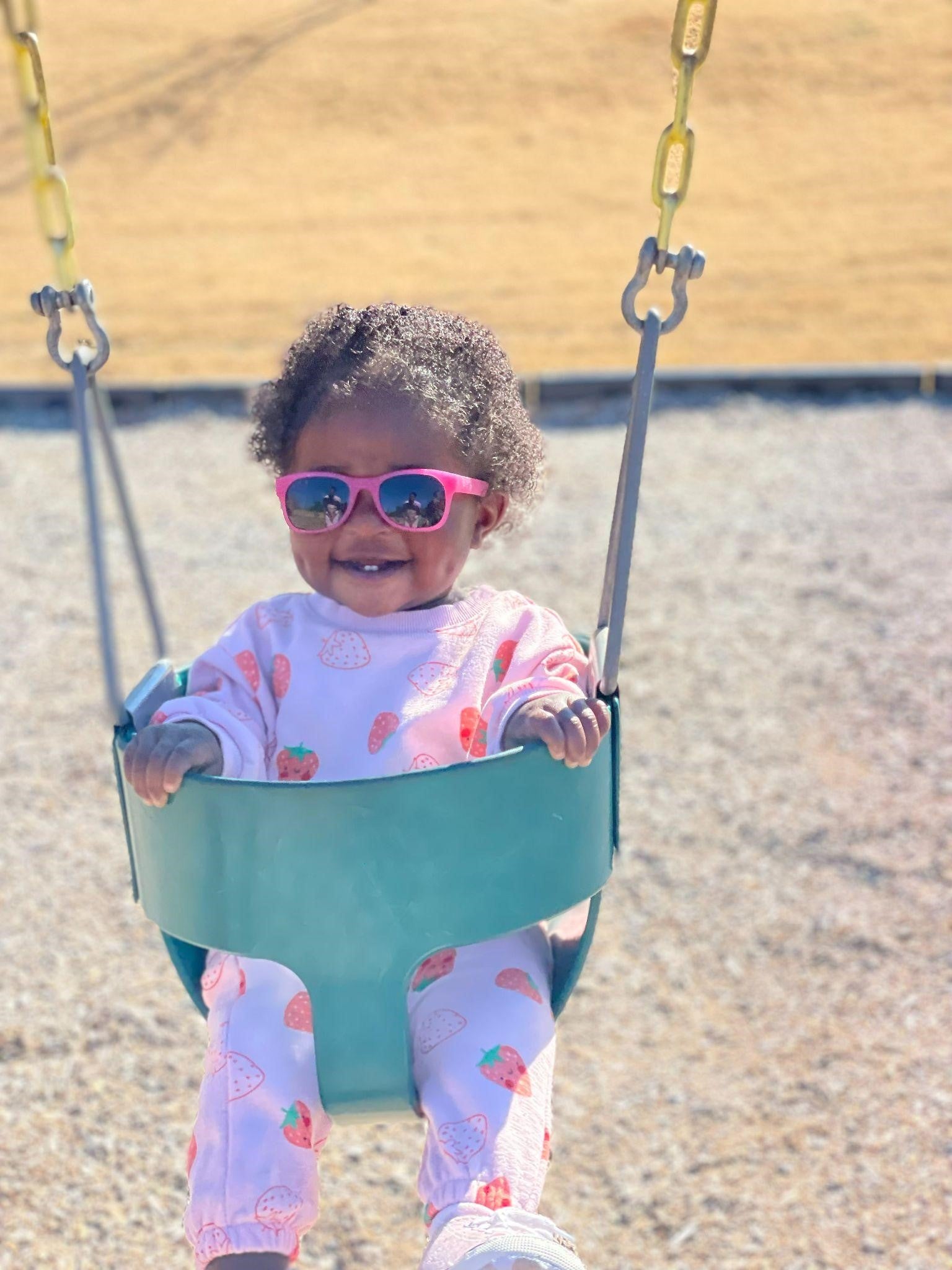 Child with sunglasses in swing